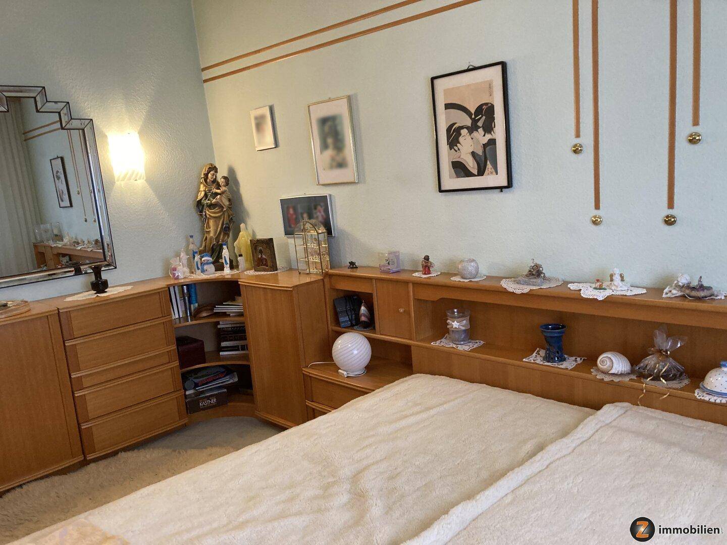 Schlafzimmer mit Doppelbett, Holzmöbeln und hellblauen Wänden, dekoriert mit Bildern.