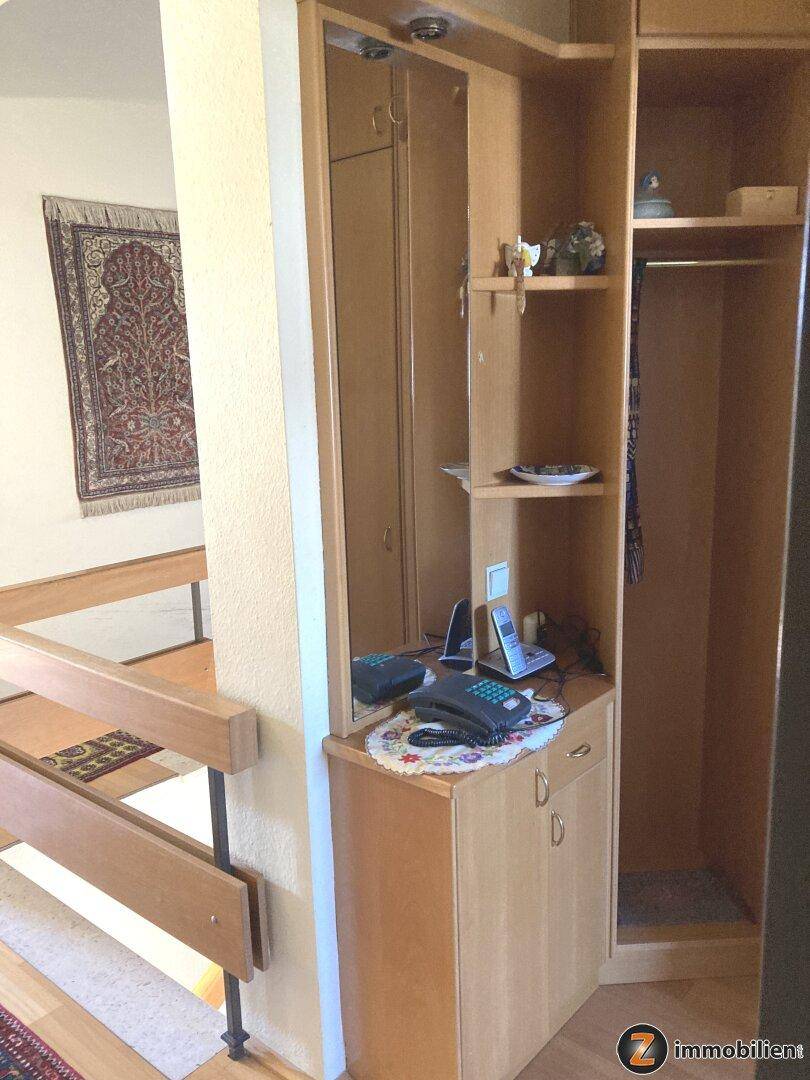 Flur mit Garderobenschrank, Spiegel und Telefon, der zu weiteren Räumen führt.
