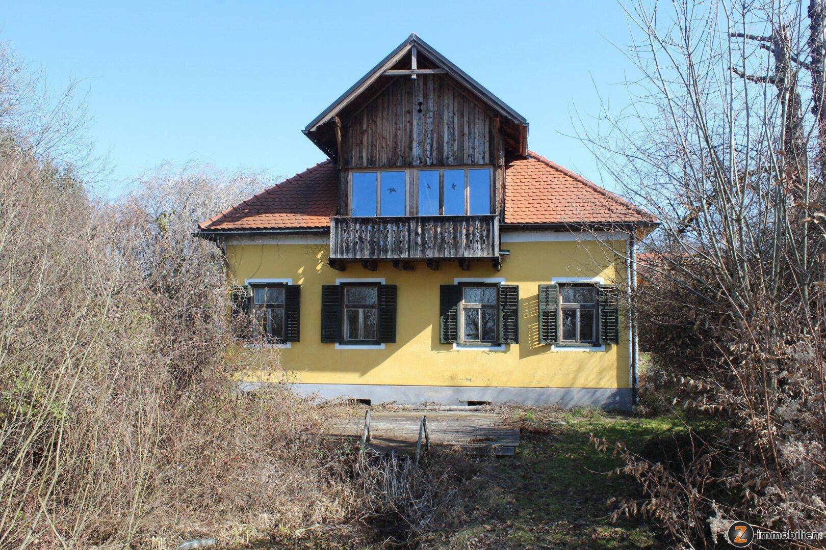 Traditionelles gelbes Haus mit Holzbalkon und grünen Fensterläden.