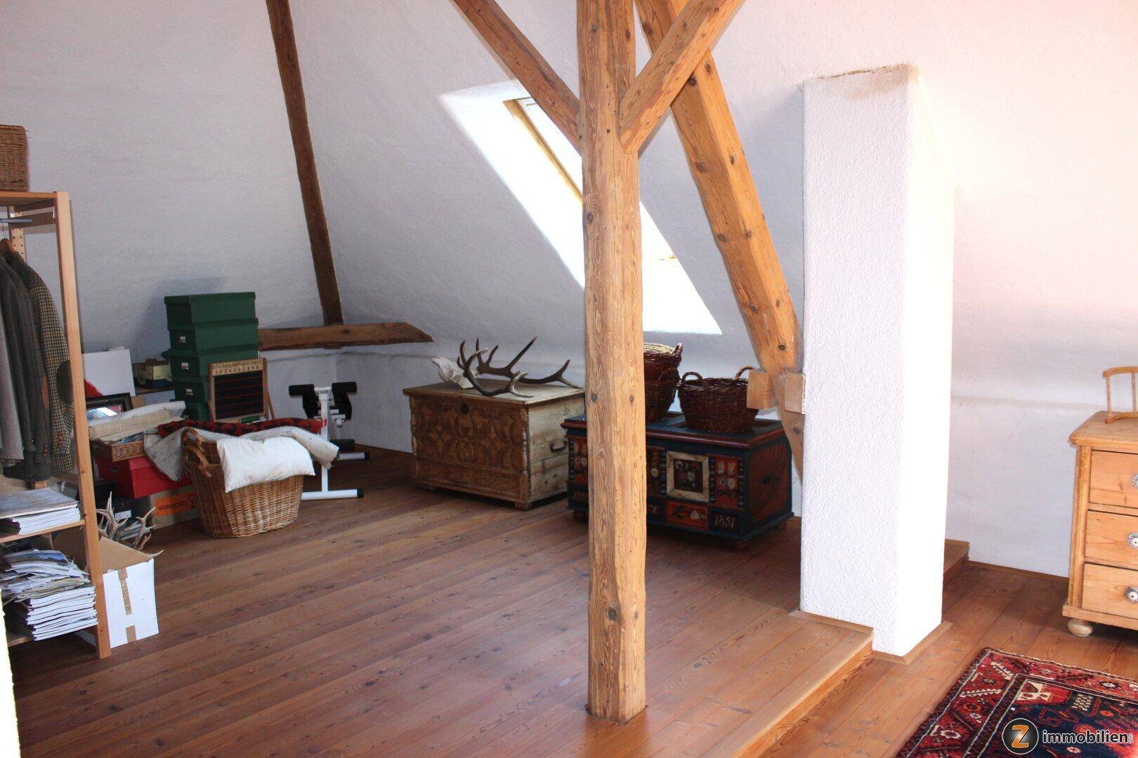 Geräumiger Dachboden mit Holzboden, Dachschrägen und traditionellen Truhen.