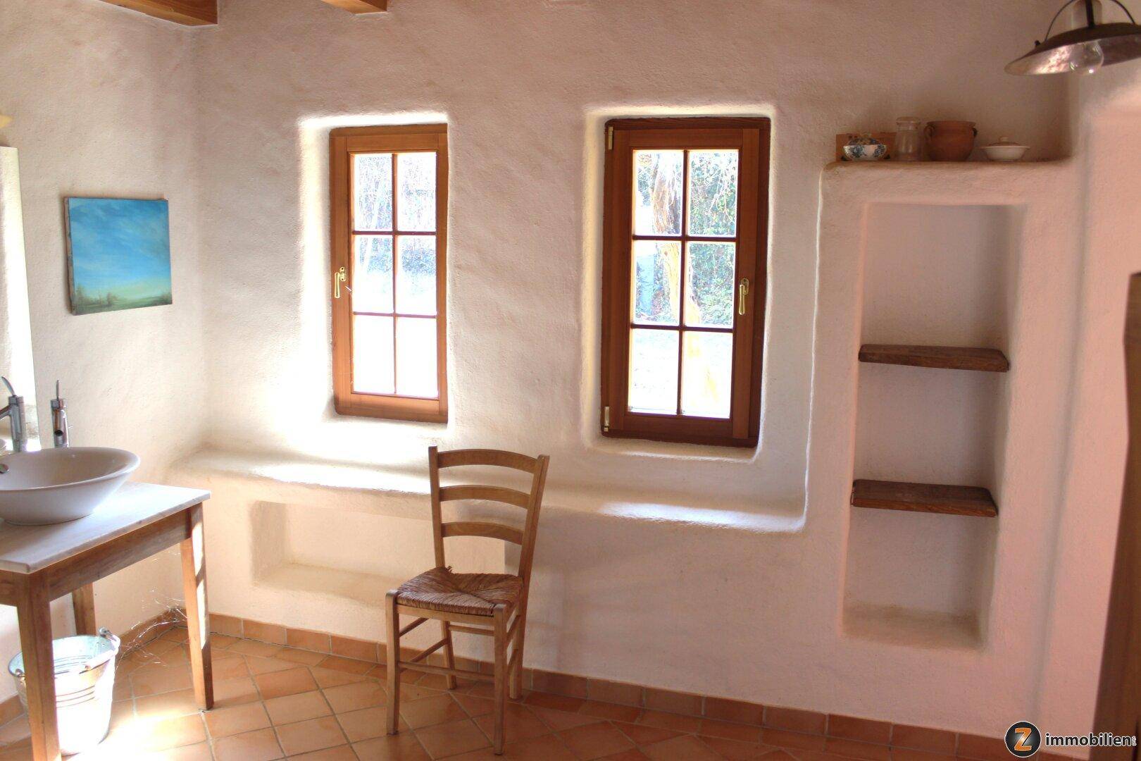 Helles Badezimmer mit Waschbecken, Fenster und rustikalen Einbauregalen.
