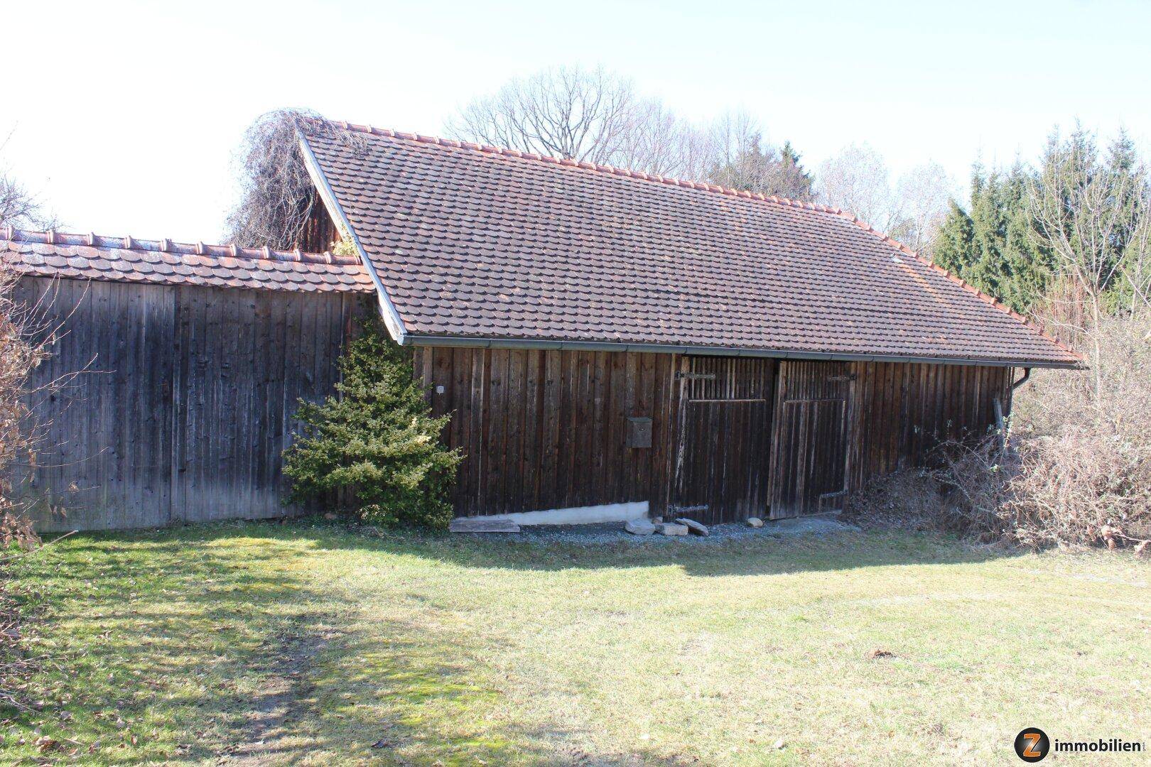 Rustikales Holzgebäude mit Ziegeldach, umgeben von Grünflächen.