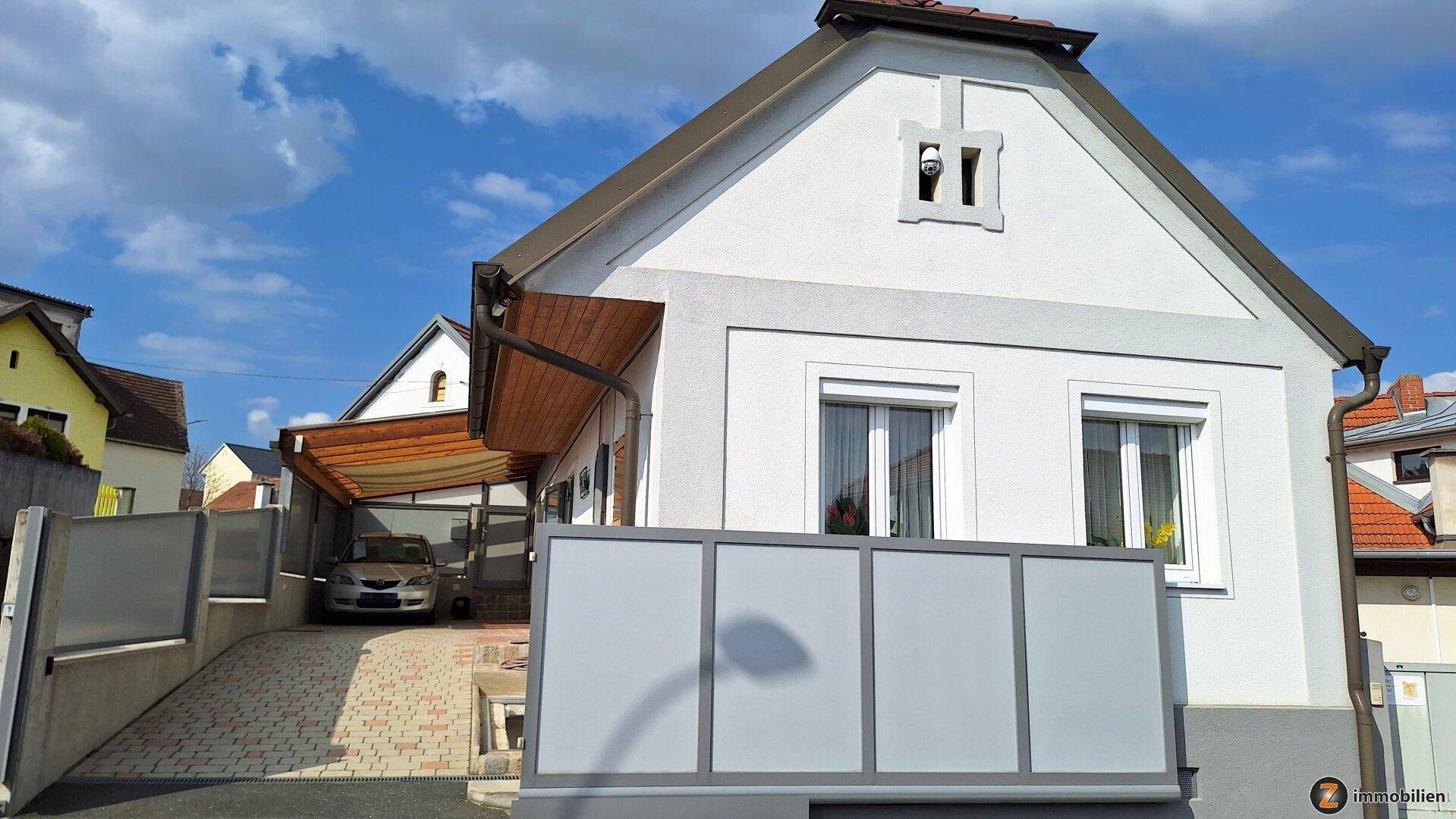 Ansicht des Hauses von der Straße mit Carport und Photovoltaikanlage auf dem Dach.