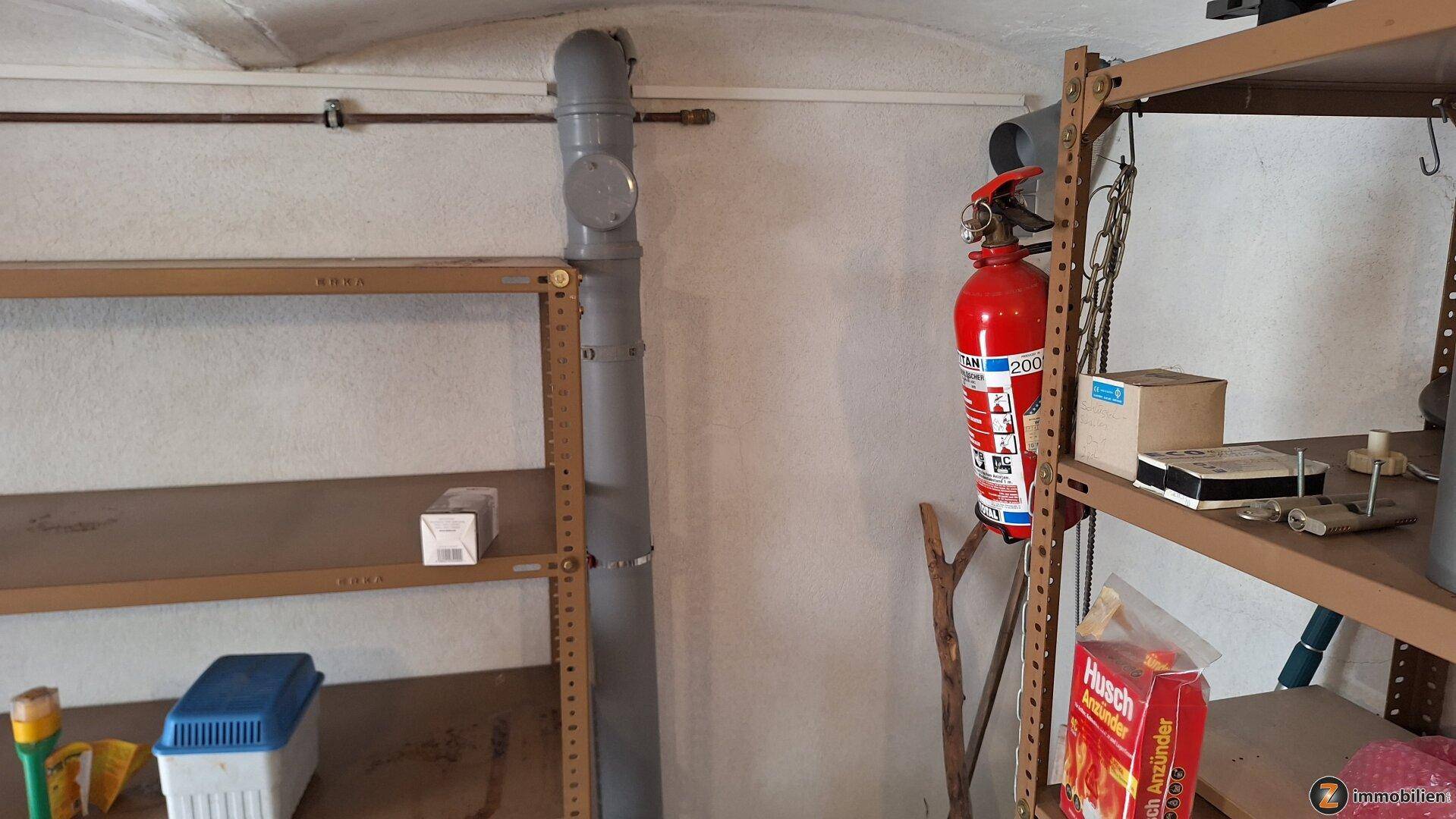 Lagerraum mit Regalen und einem Feuerlöscher, ideal für die Aufbewahrung von Haushaltsgegenständen.
