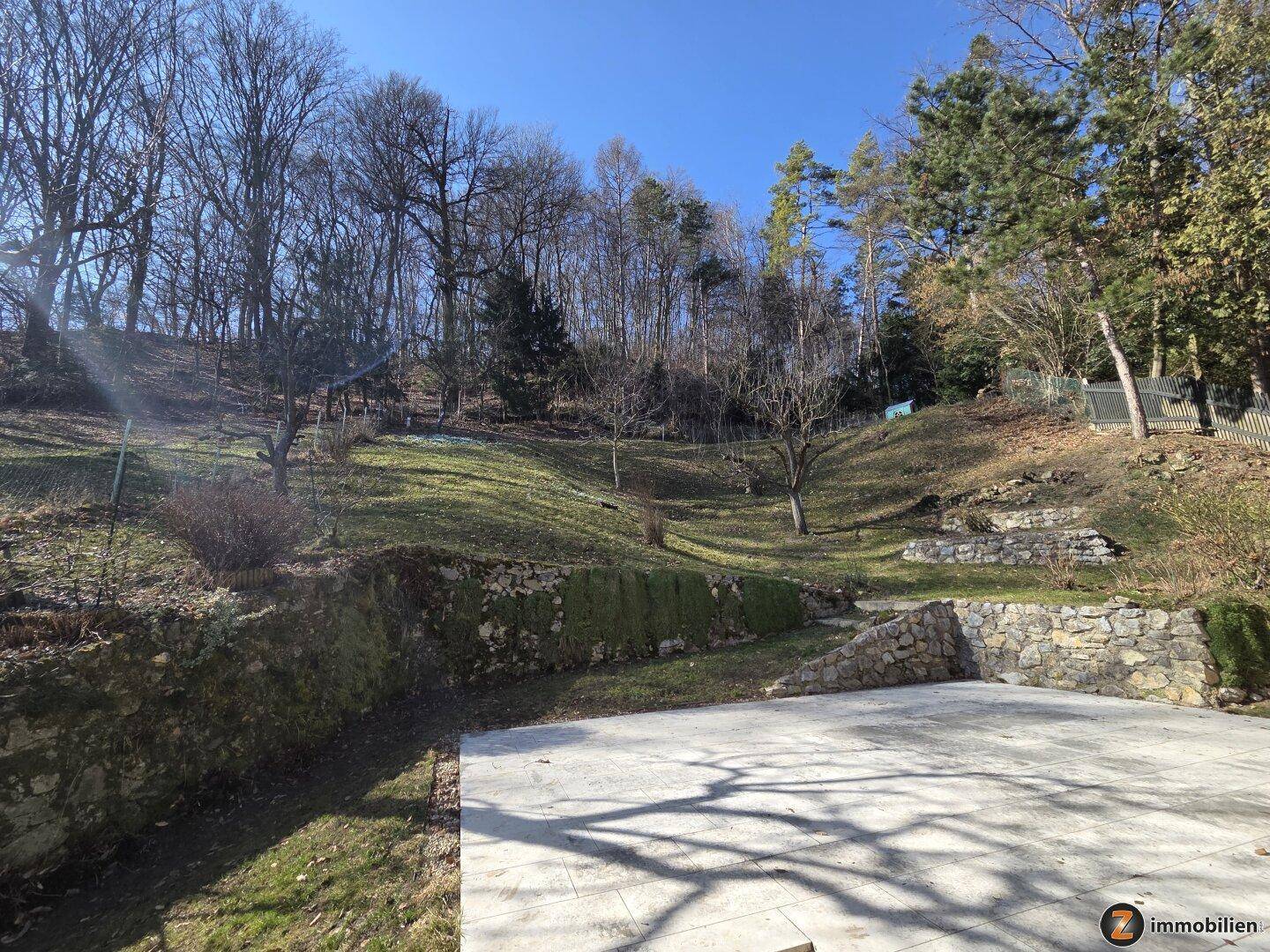 Großer, terrassierter Gartenbereich mit altem Baumbestand und Natursteinmauern am Hang.