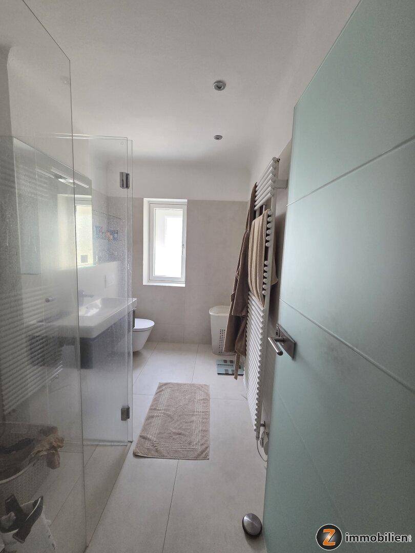 Modernes Badezimmer mit ebenerdiger Dusche, Fenster und beheiztem Handtuchhalter.
