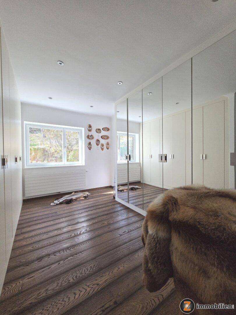 Geräumiger Ankleidebereich mit Einbauschränken, Spiegelfronten und dunklem Holzboden.