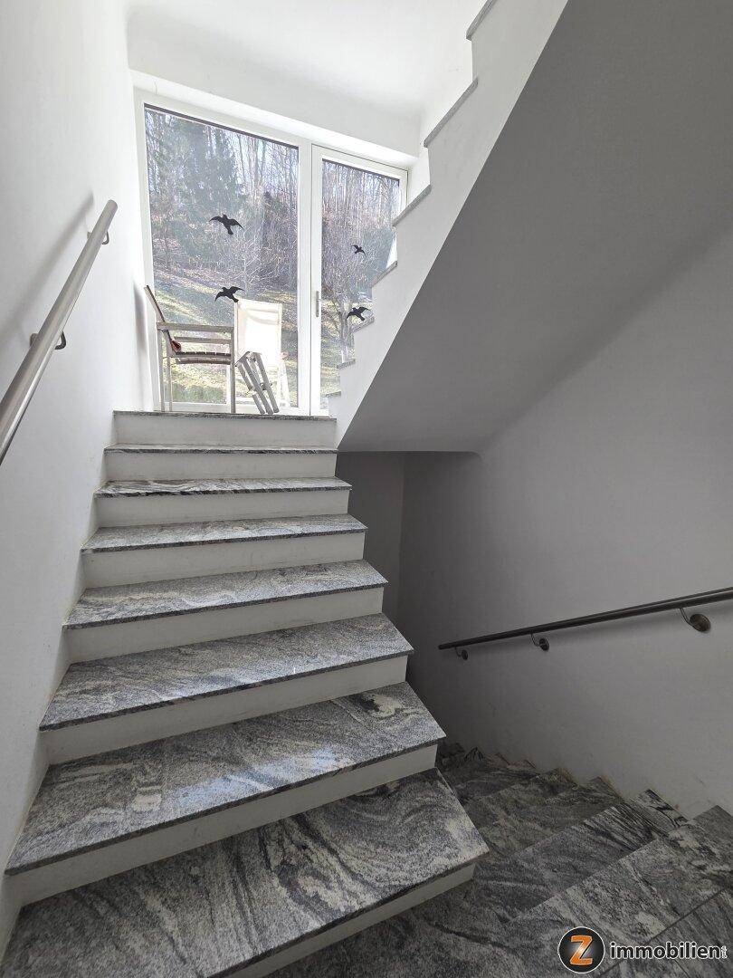 Heller Treppenaufgang mit Granitstufen und Zugang zu einem Außenbereich.