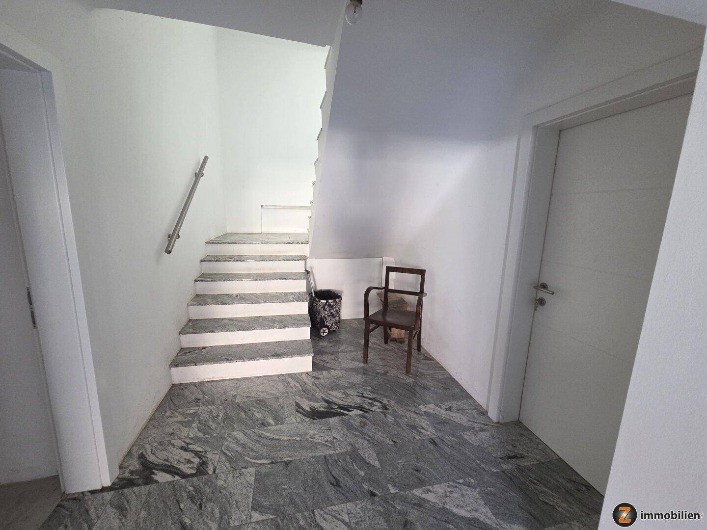 Eingangsbereich mit Granitboden und Treppe zum Obergeschoss.