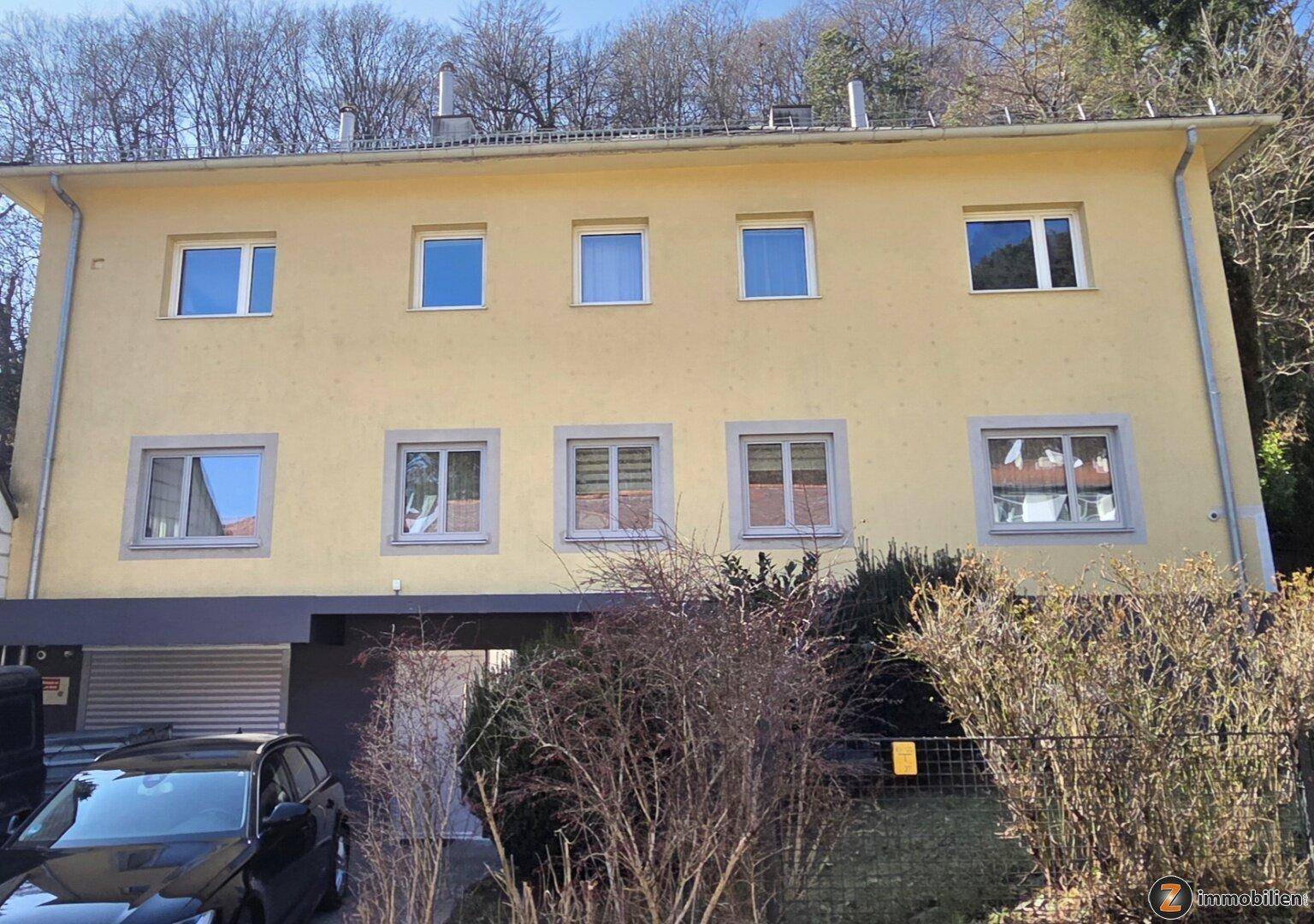 Vorderansicht des Hauses mit mehreren Fenstern und einem überdachten Eingangsbereich.