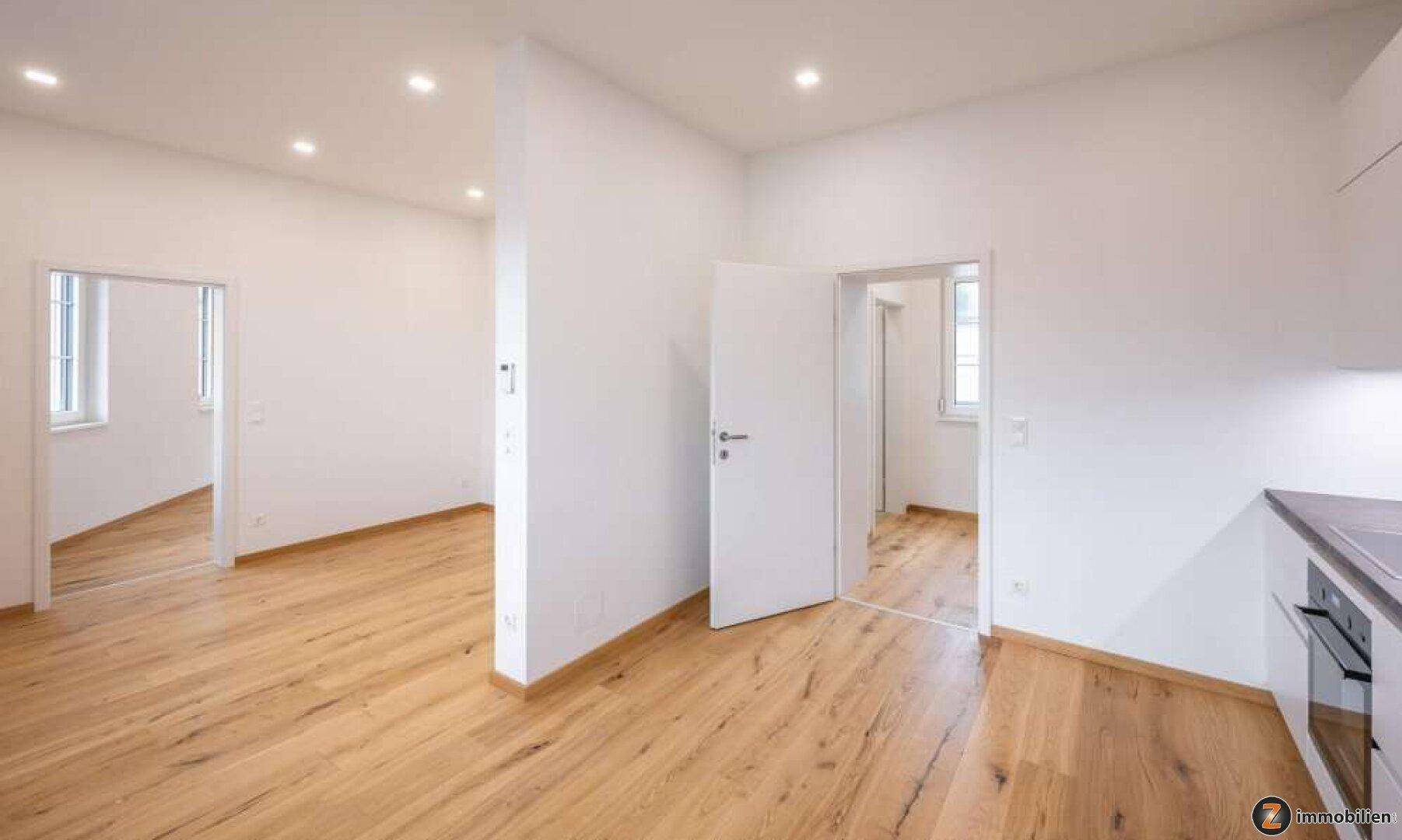 Heller, leerer Raum mit Holzboden und weißen Wänden, bereit zur individuellen Gestaltung.