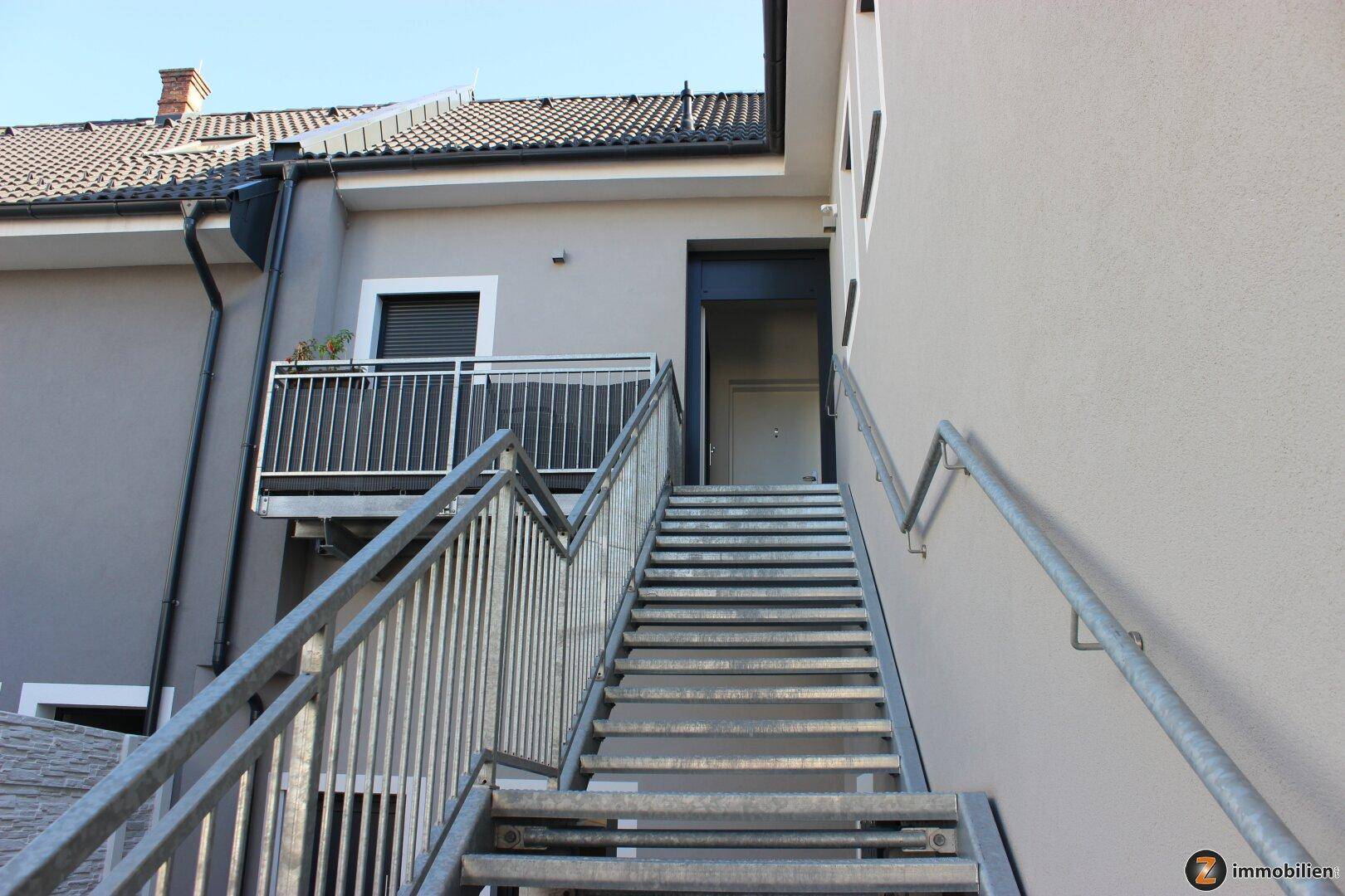 Außentreppe aus Metall führt zu einem Eingangsbereich im Obergeschoss des Gebäudes.