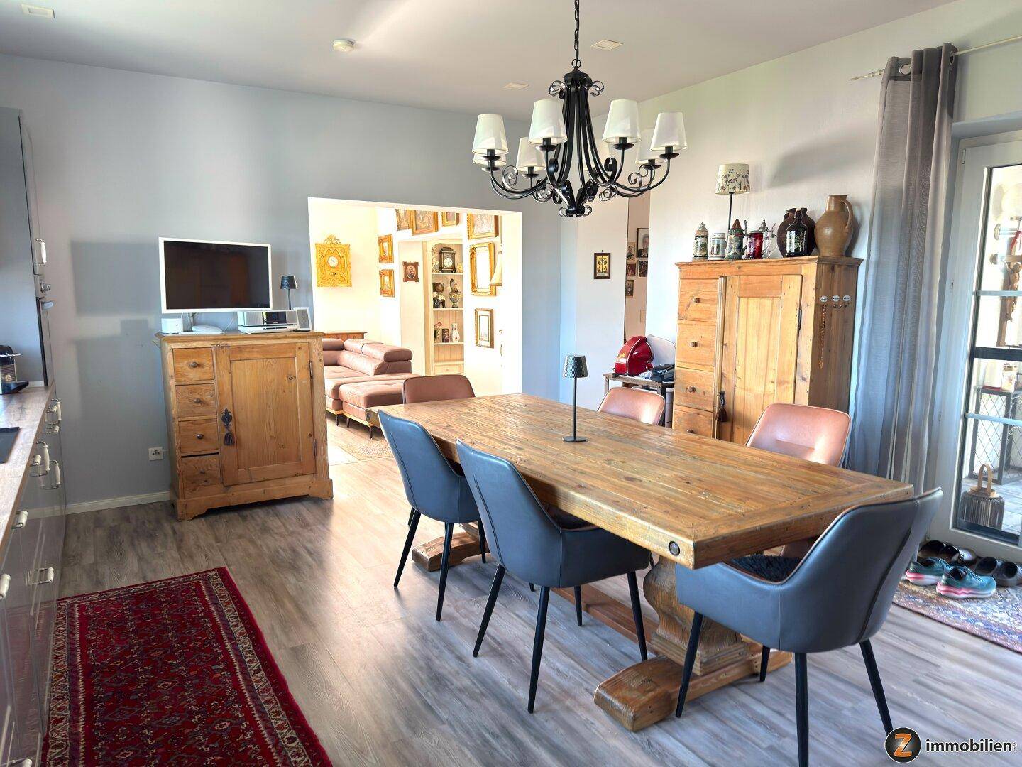 Geräumiger Wohn-Essbereich mit Holztisch, modernen Stühlen und Übergang zum Wohnzimmer.