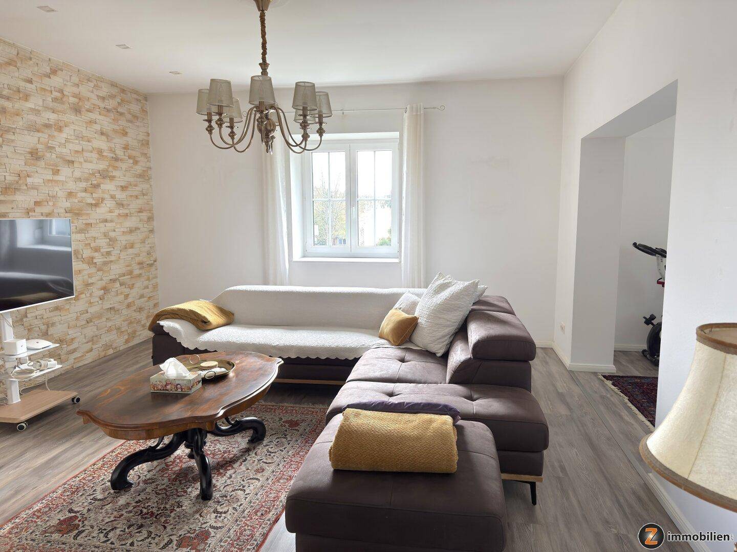 Helles Wohnzimmer mit bequemer Couch, Couchtisch und dekorativer Steinwand.
