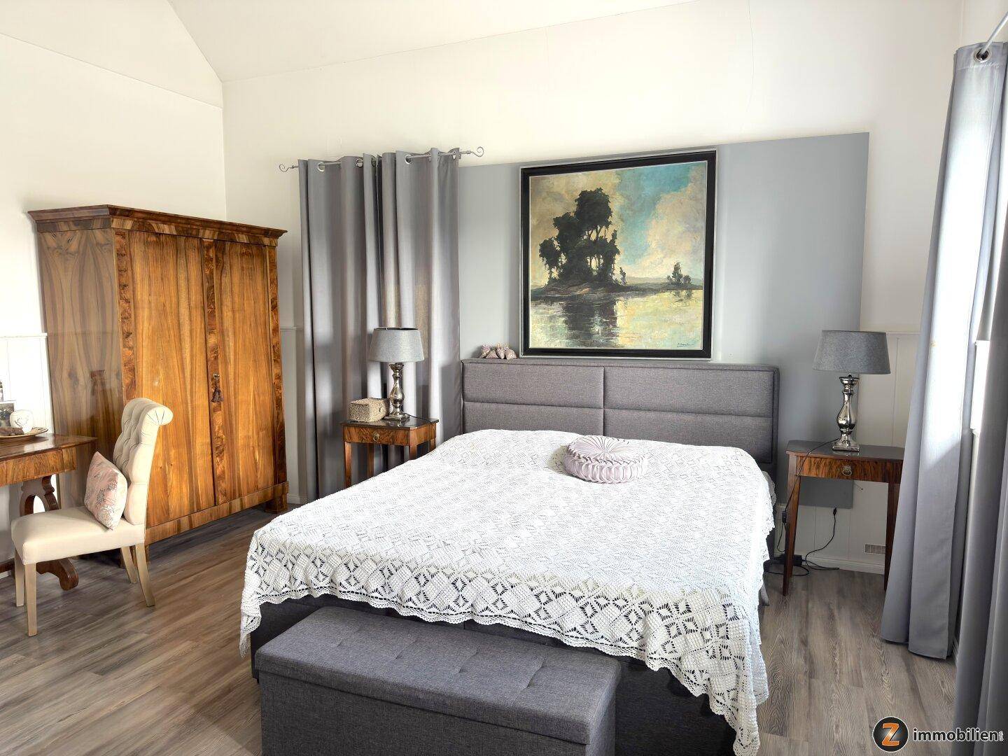 Geräumiges Schlafzimmer mit großem Bett, Holzschrank und Vorhängen.