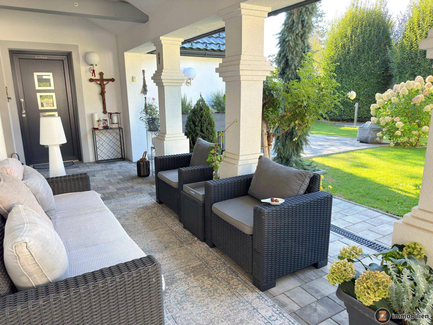 Überdachte Terrasse mit bequemen Loungemöbeln und Blick in den grünen Gartenbereich.