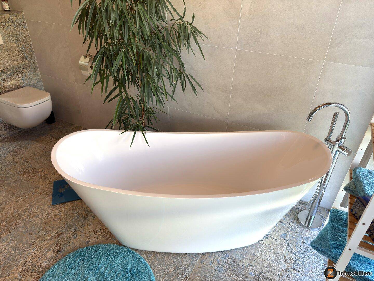 Freistehende Badewanne in einem modernen Badezimmer mit Fliesenboden.