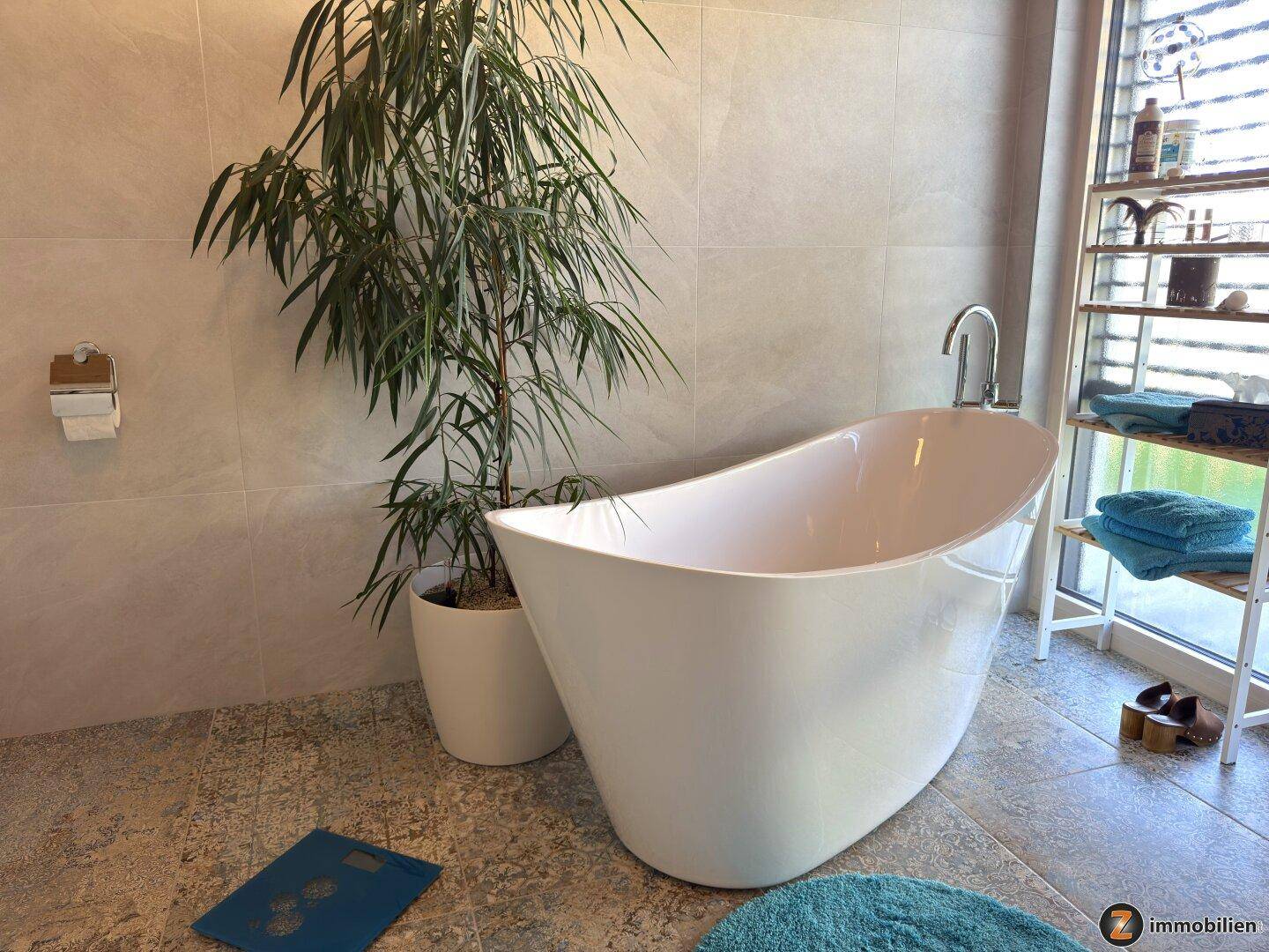 Modernes Badezimmer mit freistehender Badewanne, großformatigen Fliesen und Pflanzen.