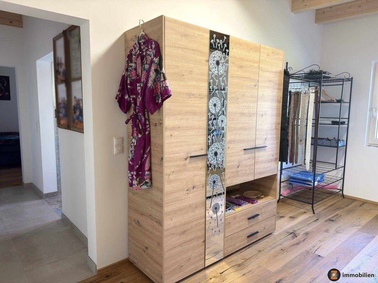 Schlafzimmer mit Holzbalkendecke, Parkettboden und großem Kleiderschrank.