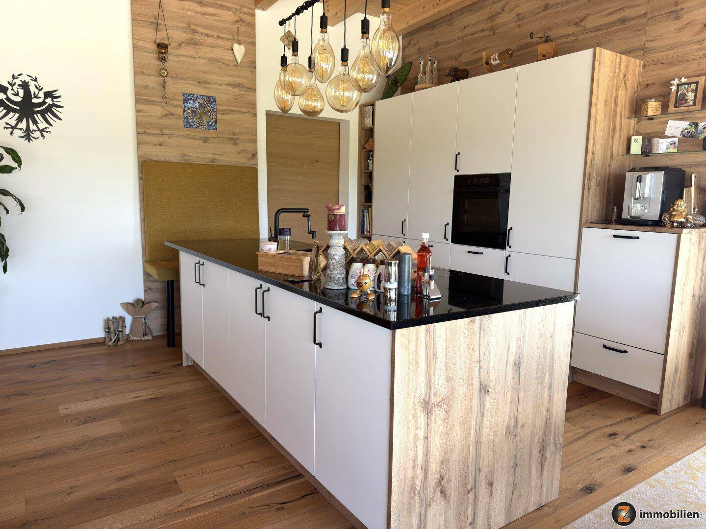 Moderne Einbauküche mit Kochinsel, schwarzen Arbeitsplatten und Holzelementen.