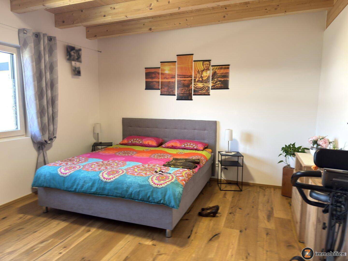 Helles Schlafzimmer mit Holzbalkendecke, Parkettboden und großem Doppelbett.