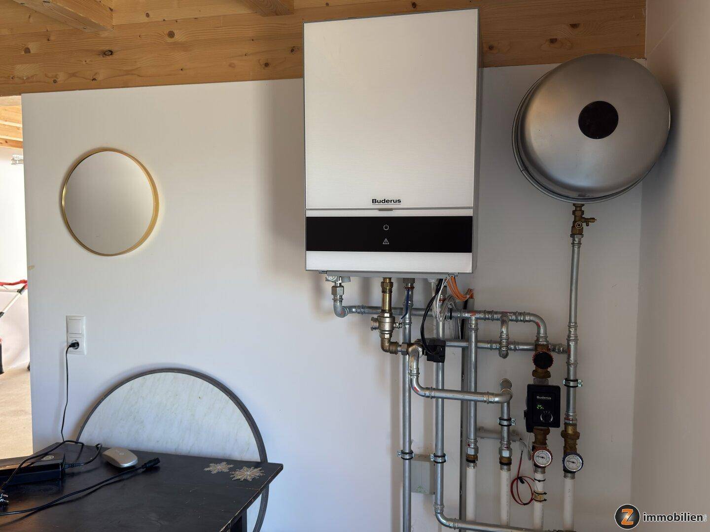 Heizungsanlage mit Warmwasserspeicher und sichtbaren Rohrleitungen in einem Technikraum.