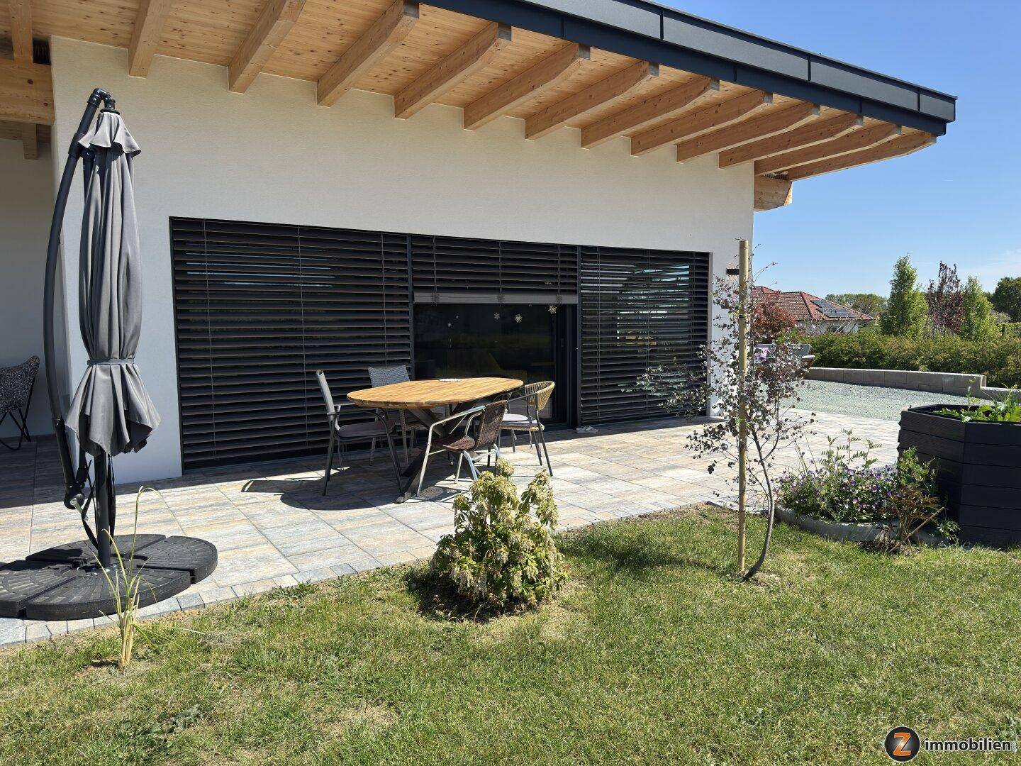 Teilansicht der Terrasse mit Gartenmöbeln und angrenzendem Rasenbereich.