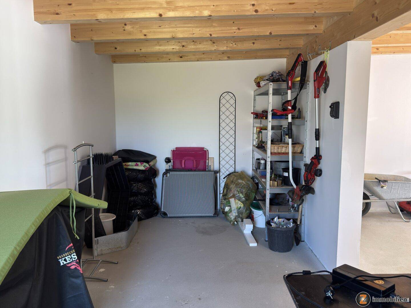 Geräumiger Abstellraum oder Garagenbereich mit Regalen und Gartengeräten.