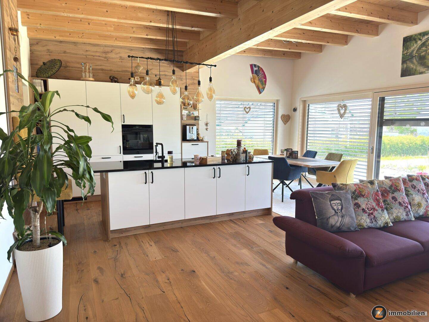 Offener Wohnbereich mit moderner Küche, Holzbalkendecke und Zugang zur Terrasse.