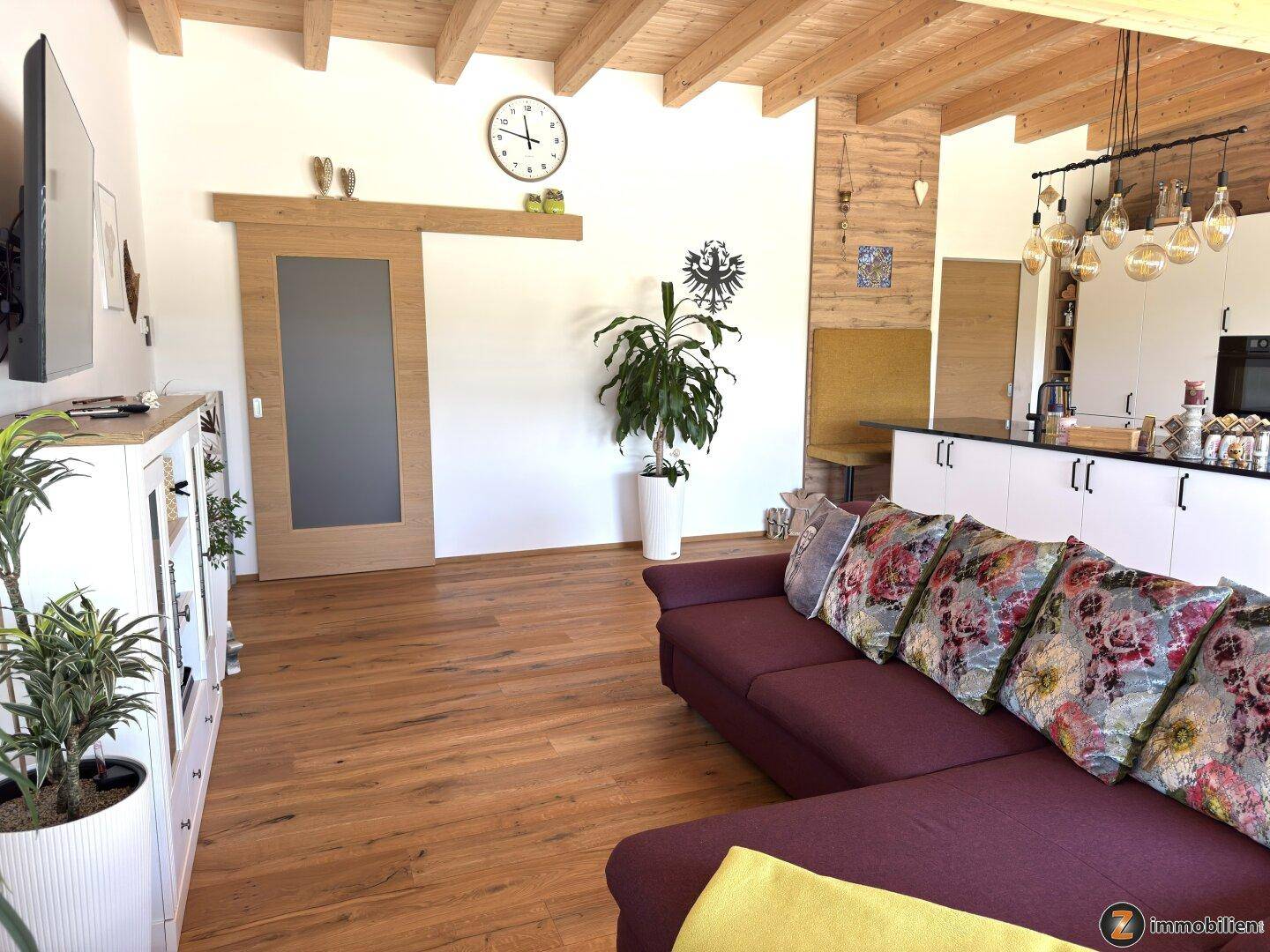 Gemütliches Wohnzimmer mit Holzbalkendecke, Parkettboden und großem Sofa.