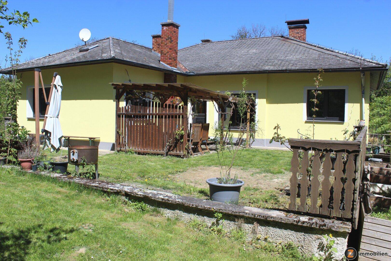 Hinterhof mit Rasenfläche, Holzpergola und Gartenmöbeln.