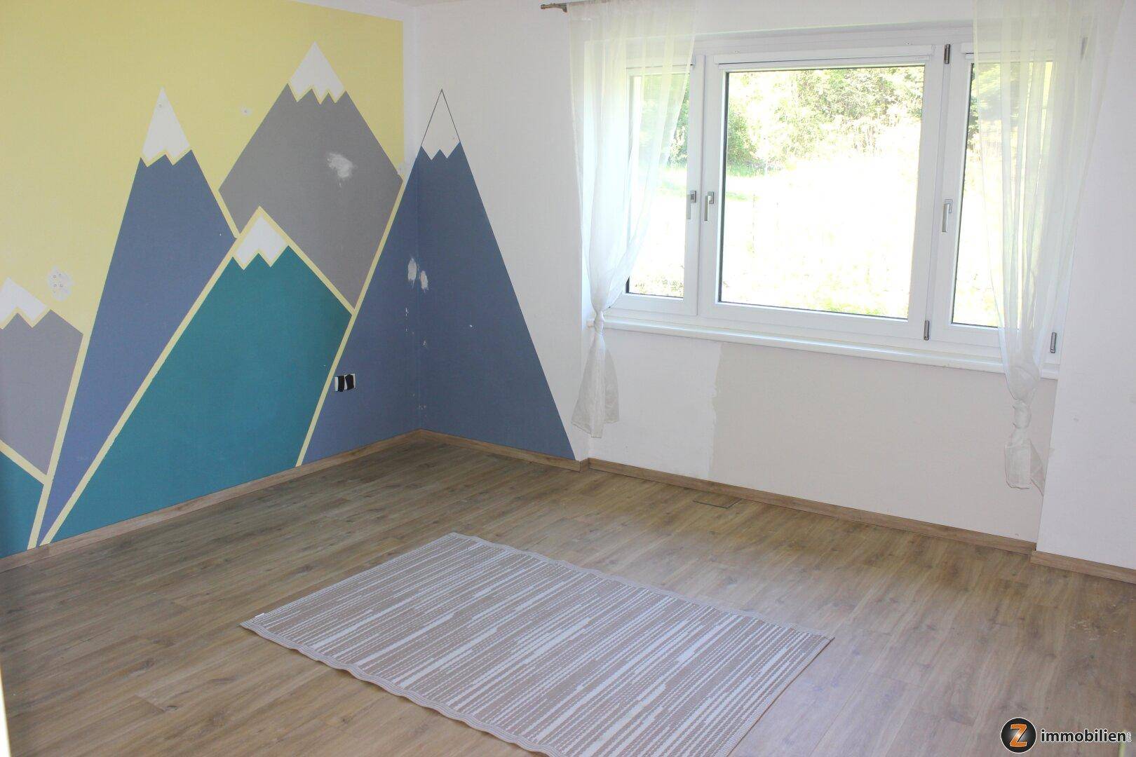 Kinderzimmer oder Gästezimmer mit Laminatboden und kreativer Bergwandmalerei.
