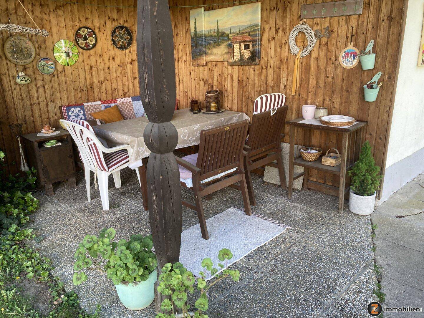 Gemütlicher überdachter Terrassenbereich mit Holzwänden und rustikalen Möbeln.