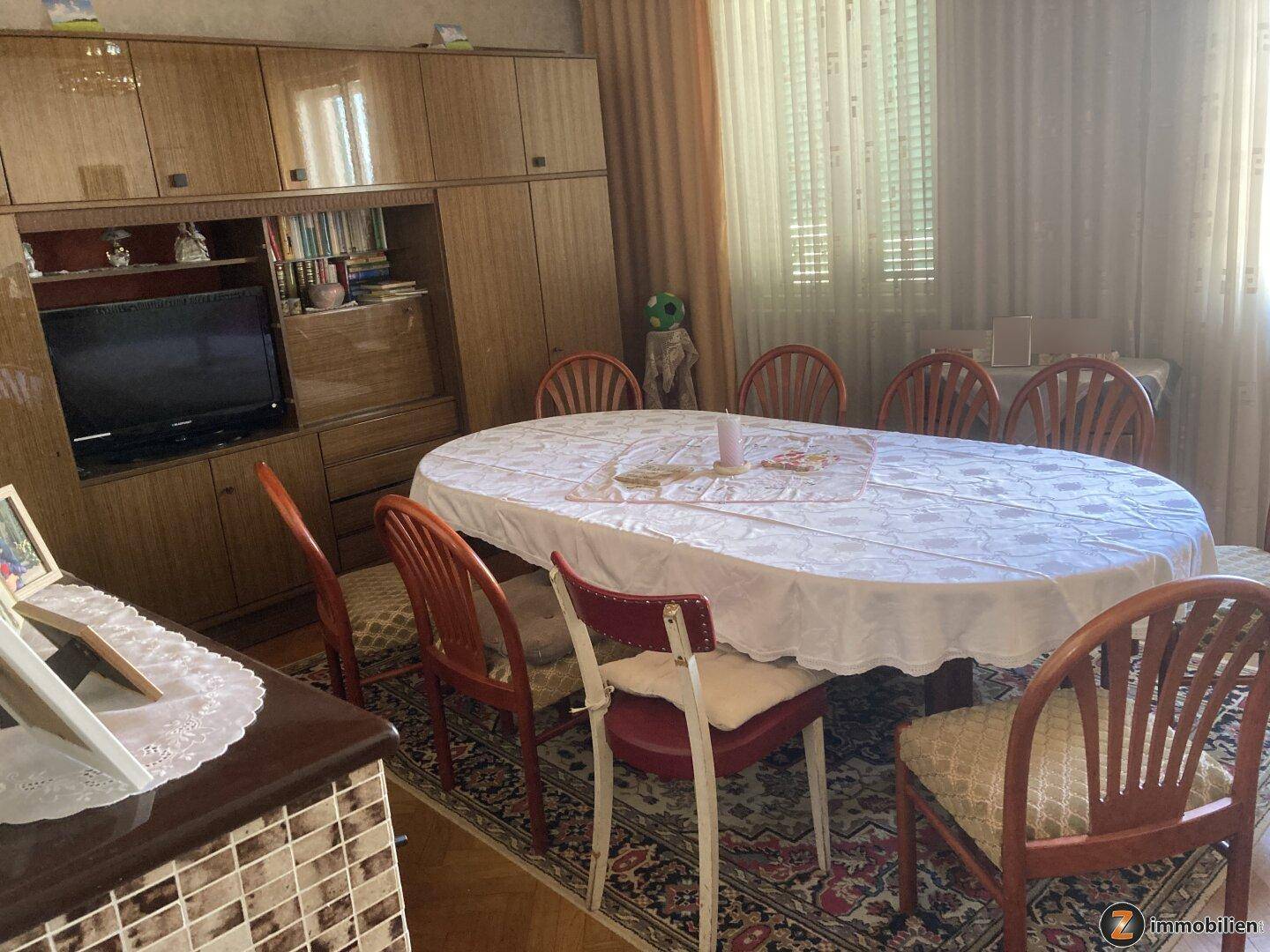 Geräumiges Esszimmer mit großem ovalen Tisch, Holzmöbeln und Teppichboden.