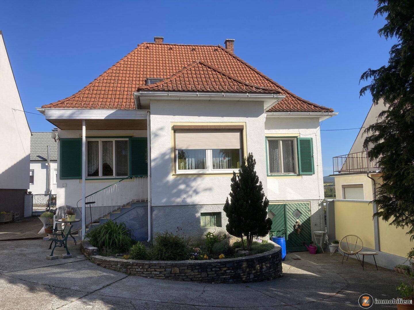 Vorderansicht des Hauses mit gepflasterter Auffahrt und kleinem Vorgarten.