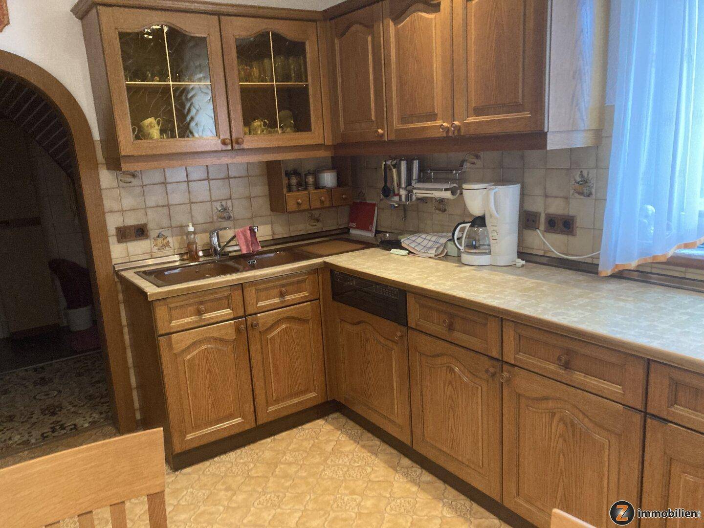 Klassische Holzküche mit Einbauschränken, Fliesenrückwand und Spülmaschine.
