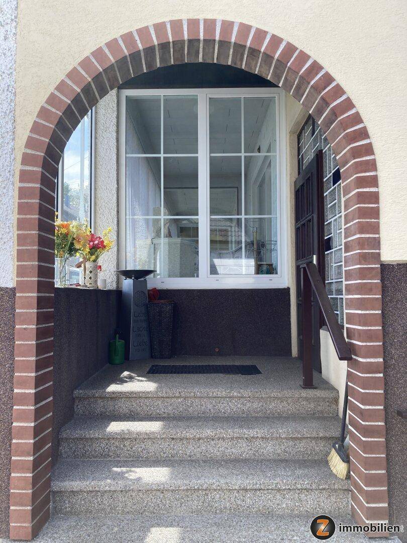 Eingangsbereich des Hauses mit gemauertem Bogen und Treppe.