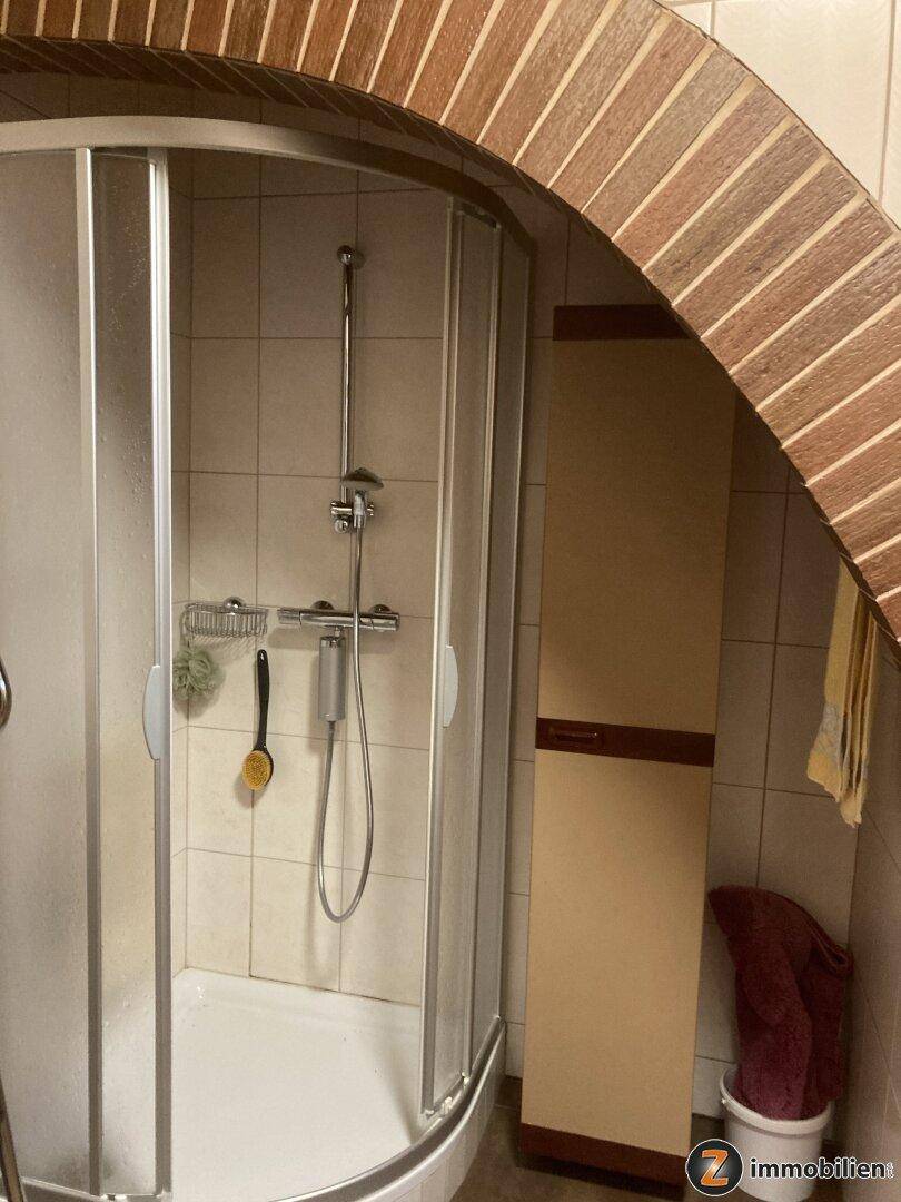 Duschbereich mit Fliesenwänden und gemauertem Bogen im traditionellen Stil.
