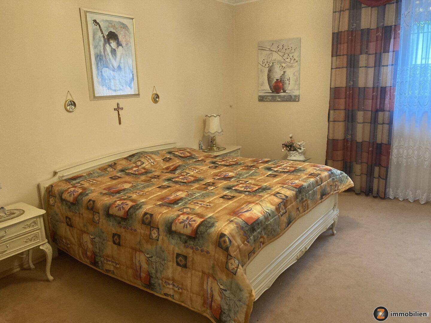 Schlafzimmer mit großem Bett, Teppichboden und traditioneller Dekoration.