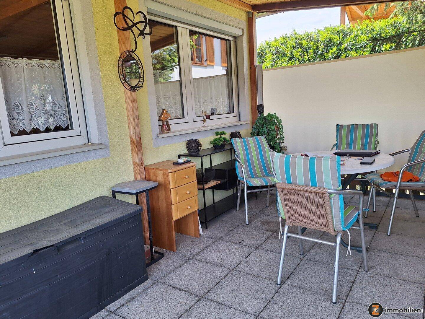 Gemütliche, überdachte Terrasse mit Gartenmöbeln und Blick in den grünen Garten.