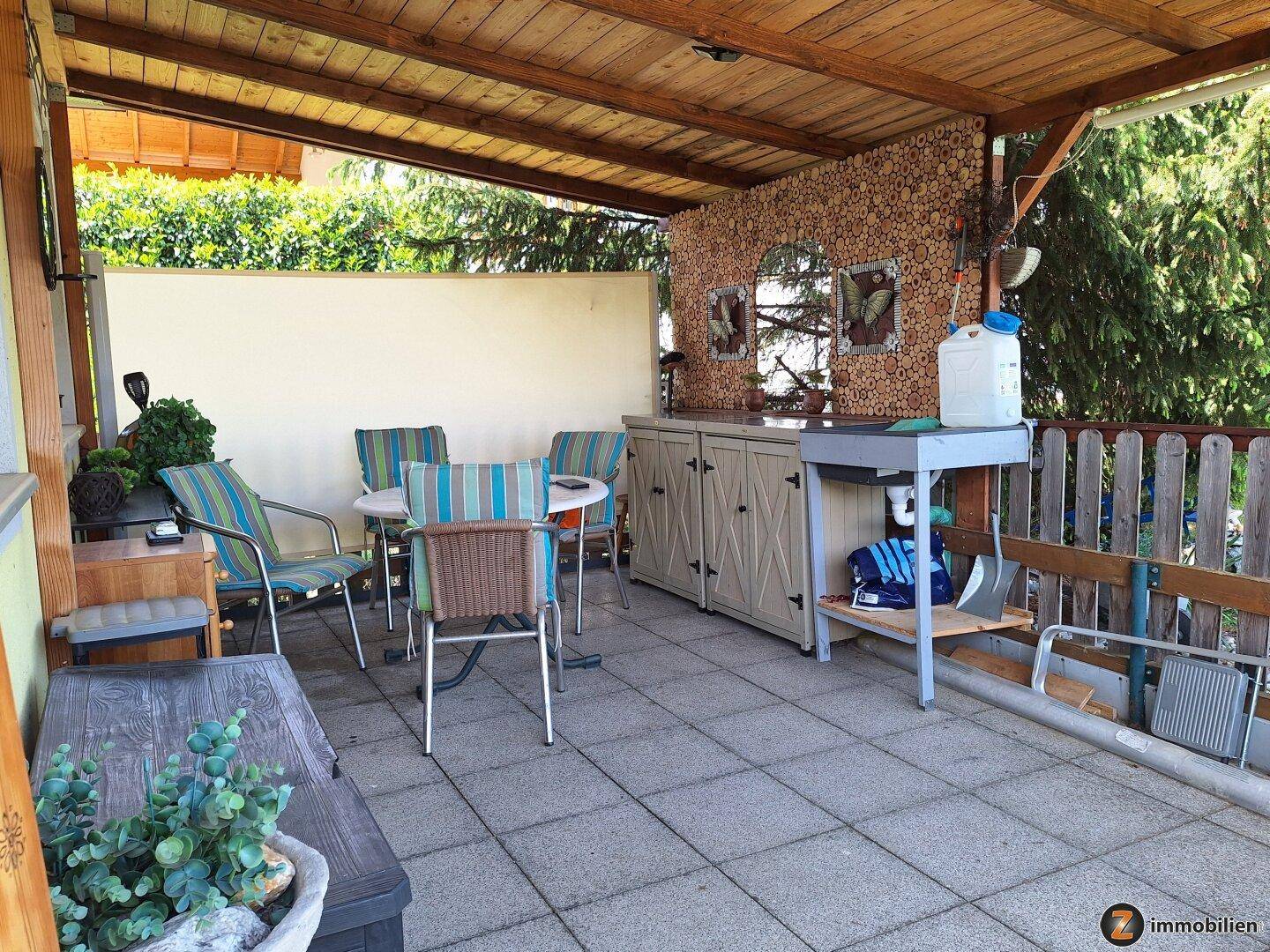 Geräumige, überdachte Terrasse mit Sitzgelegenheiten und einer rustikalen Außenküche.