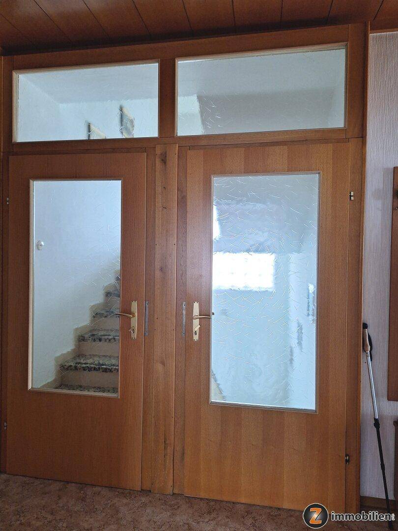 Holztüren mit Glaseinsätzen führen zu einem Treppenhaus, das Licht in den Flur bringt.