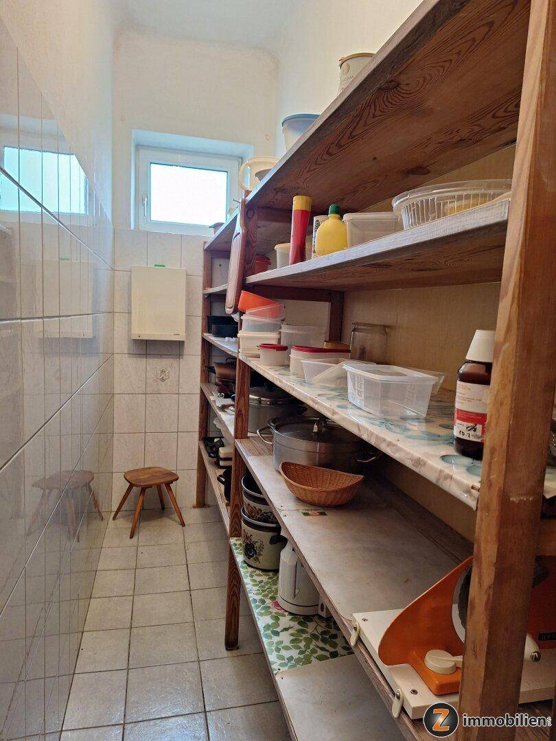 Praktische Speisekammer mit Holzregalen, gefliesten Wänden und einem kleinen Fenster.