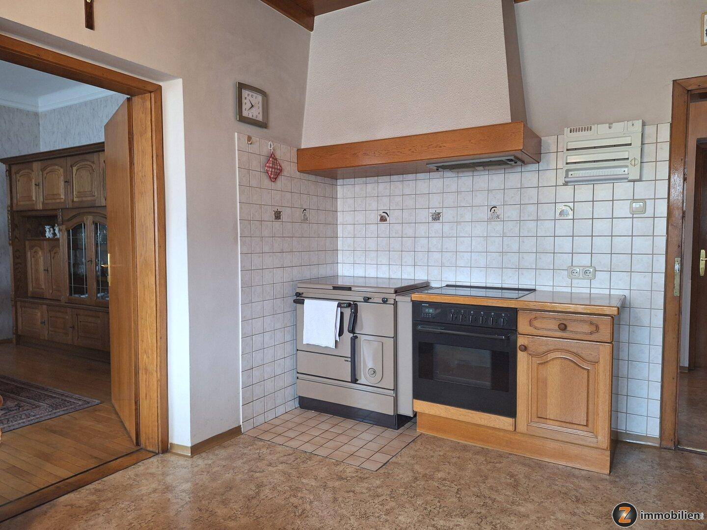 Küchenzeile mit traditionellem Herd, Backofen und gefliestem Spritzschutz in hellem Design.