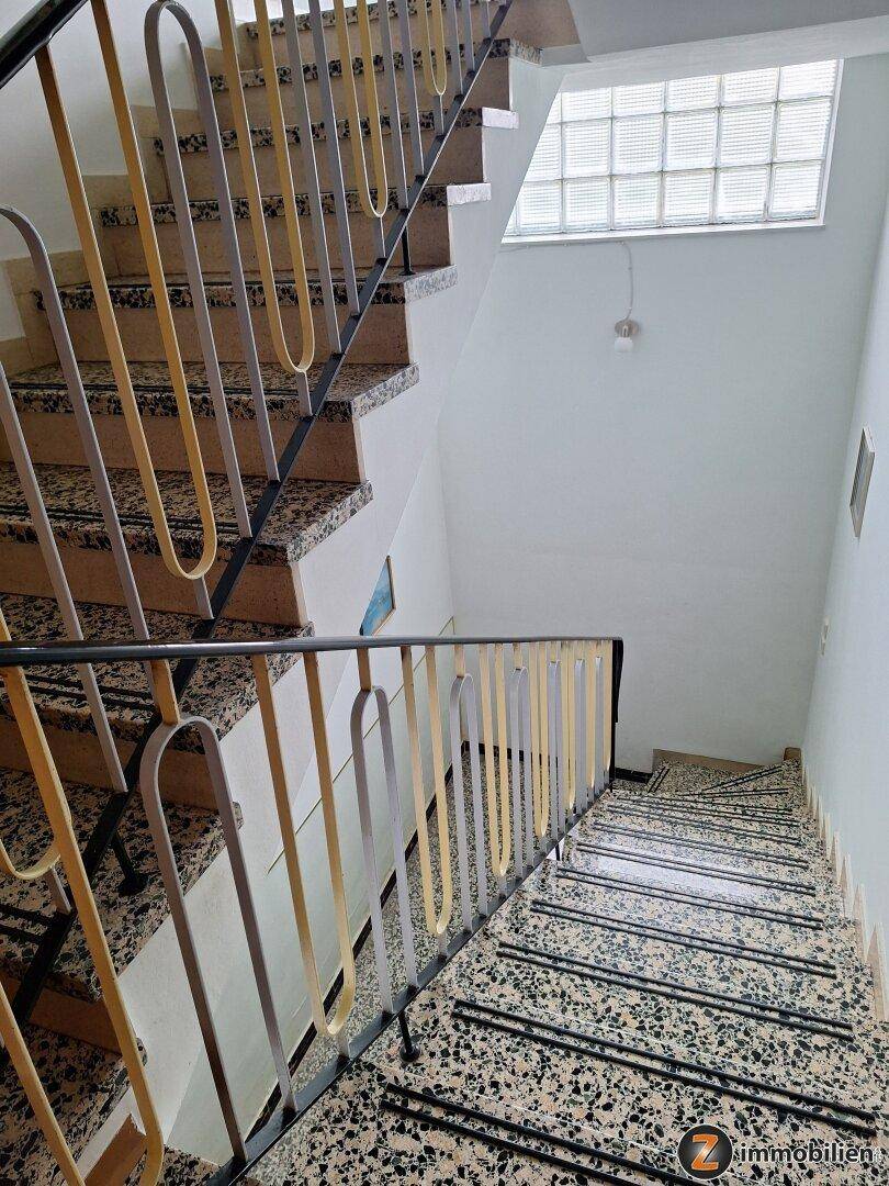 Treppenhaus mit Terrazzostufen und einem Geländer im Stil der 70er oder 80er Jahre.
