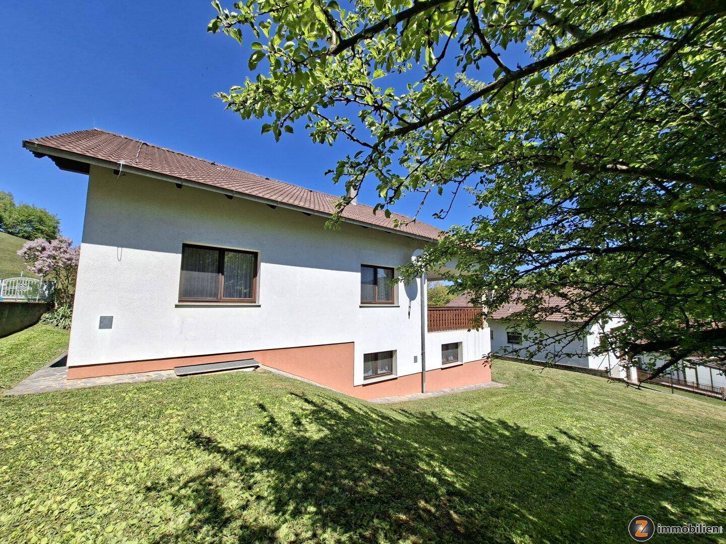 Rückansicht des Hauses mit Garten, Rasenfläche und Blick auf die grüne Umgebung.