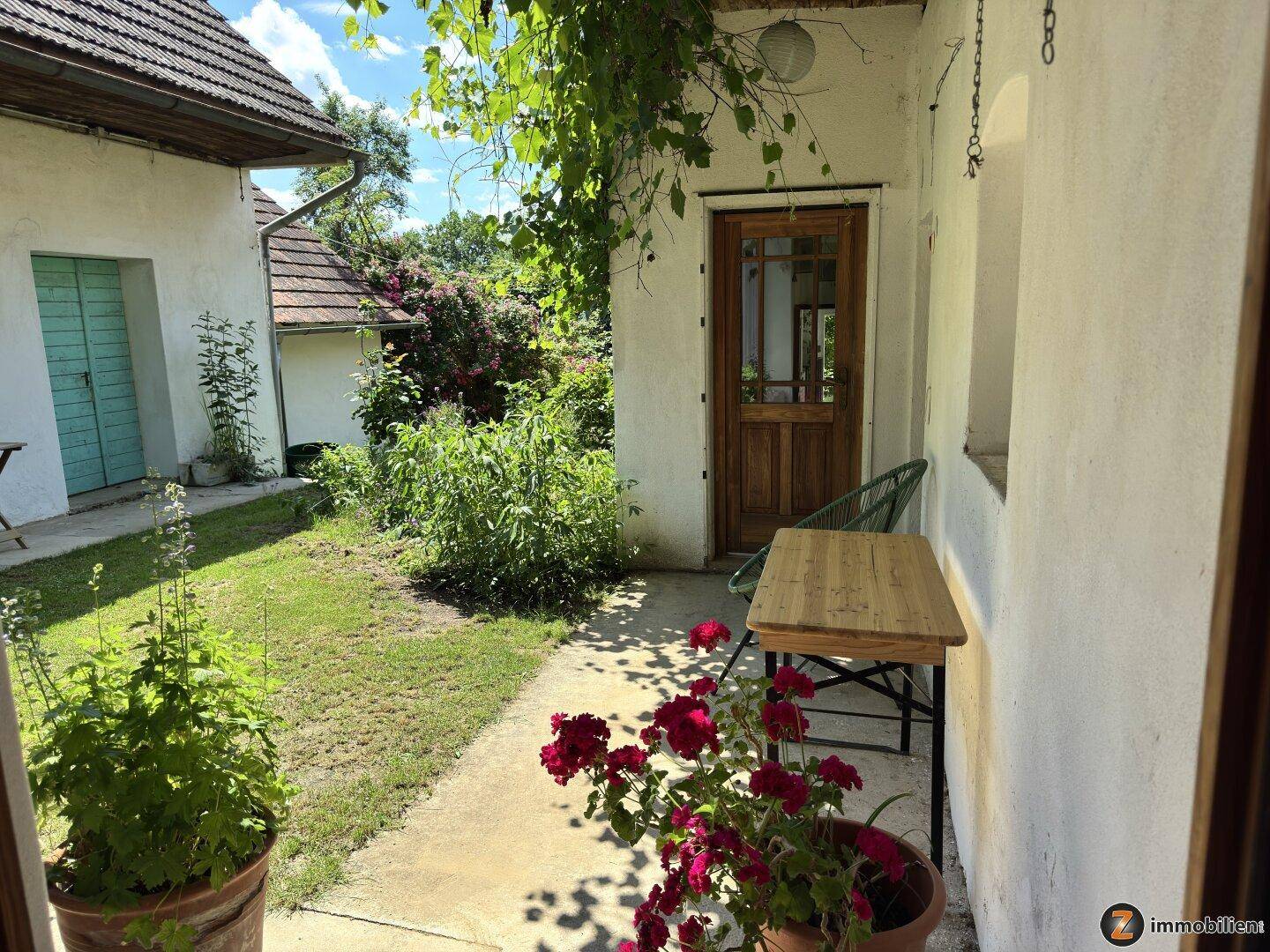 Kleiner Gartenbereich mit Sitzgelegenheit, Pflanzen und Zugang zum Haus.