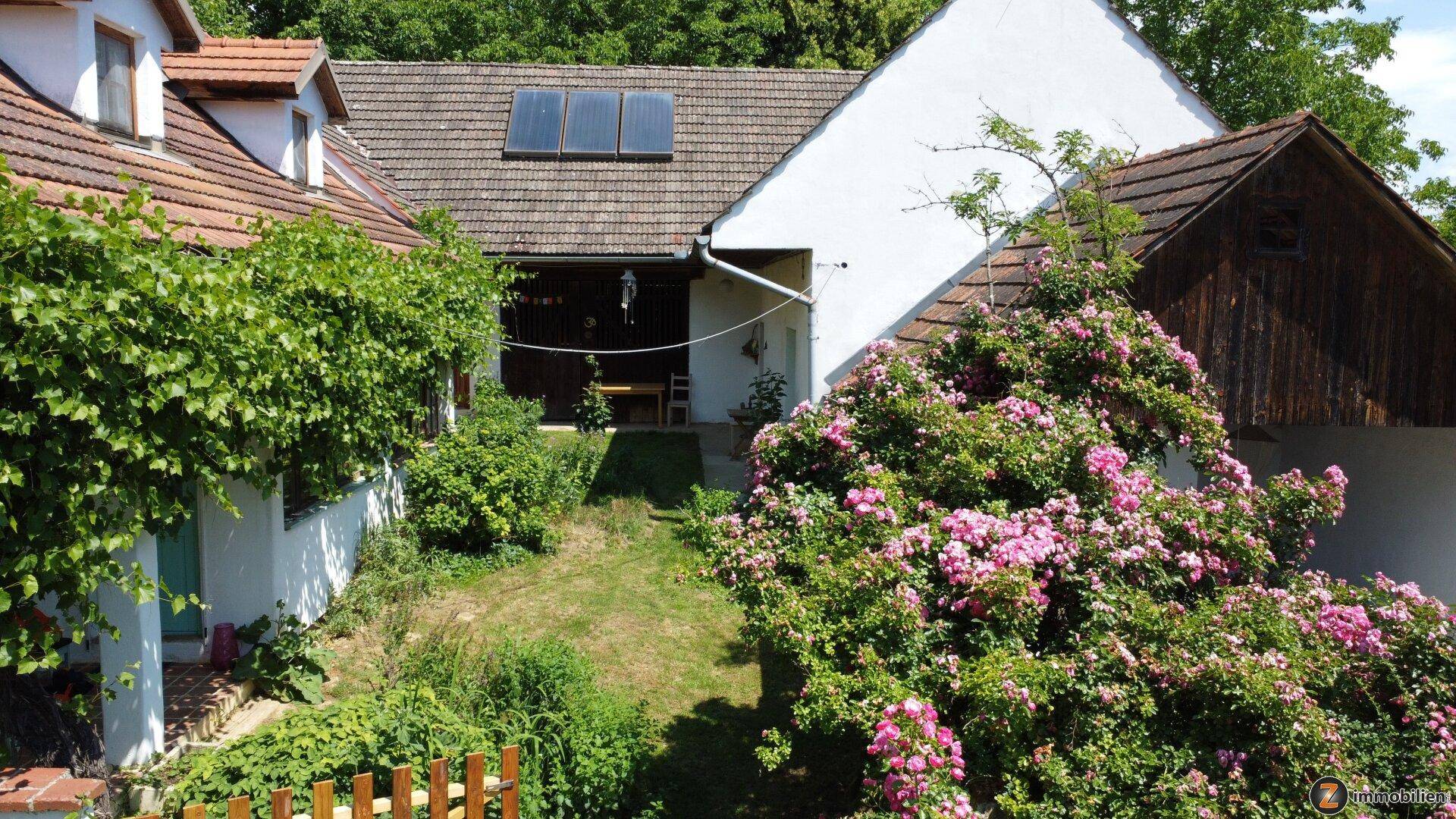 Vogelperspektive des Hauses mit weitläufigem Garten, bewachsenen Fassaden und Solarpaneelen auf dem Dach.
