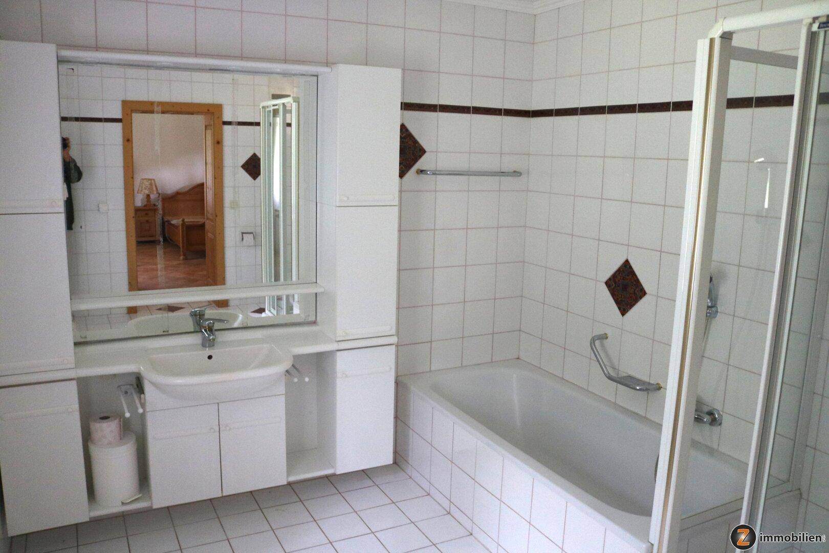 Badezimmer mit Badewanne, Dusche, Waschbecken und weißen Fliesen.