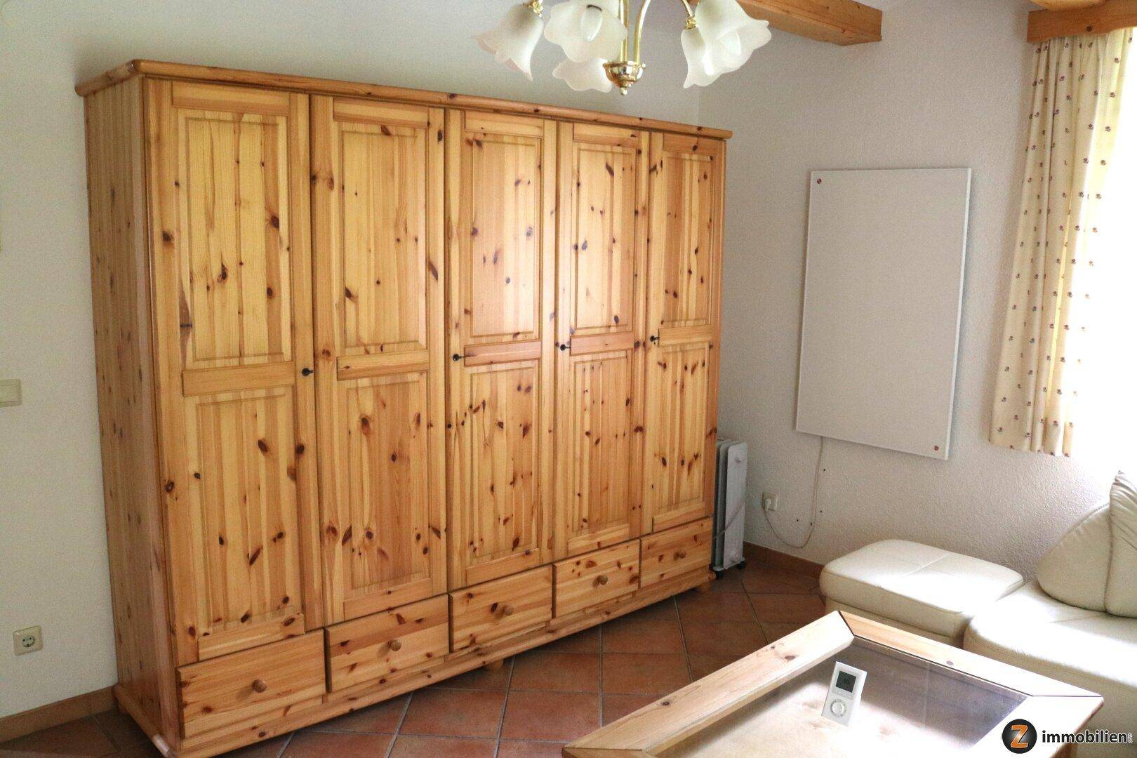 Geräumiges Zimmer mit großem Holzschrank und Terrakottafliesen.